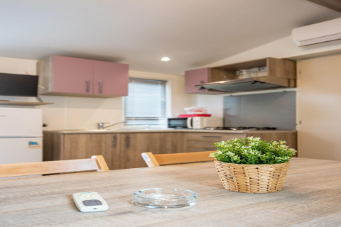 Moderne mobilhome-køkken i Torre del Sol Cottage, Spanien, med træbord, plante og køkkenredskaber.