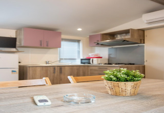 Moderne mobilhome-køkken i Torre del Sol Cottage, Spanien, med træbord, plante og køkkenredskaber.