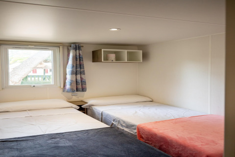 Værelse i Torre del Sol Cottage mobilhome i Spanien, med tre enkeltsenge, vindue og minimalistisk indretning.