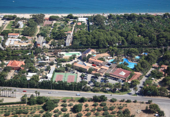Vista aerea di un glamping con piscina, campi da tennis, parcheggio e spiaggia sabbiosa nelle vicinanze.