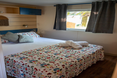 Dormitorio en Torre del Sol COTTAGE ACACIA, España, con cama doble, ropa de cama floral y ventana luminosa.