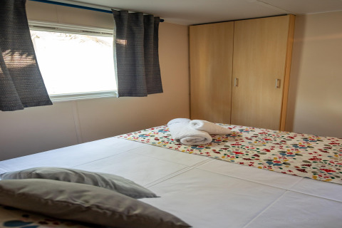 Dormitorio en Torre del Sol COTTAGE ACACIA, España, con cama doble, armario y colcha colorida.