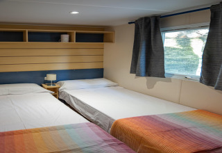 Habitación del Torre del Sol COTTAGE ACACIA en España, con tres camas individuales, mantas coloridas y ventana.