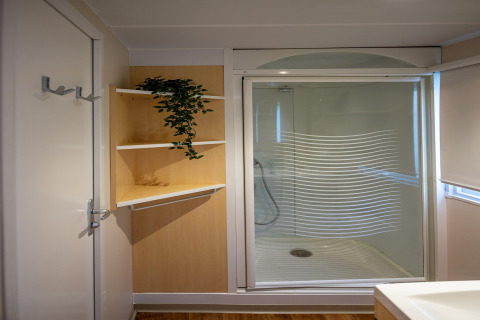 Baño moderno en Torre del Sol COTTAGE ACACIA, España, con cabina de ducha y estantes con una planta decorativa.