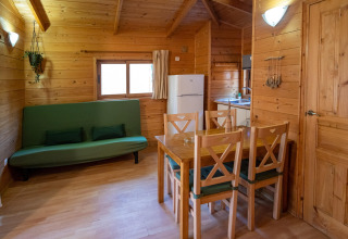 Vista interior del TORRE DEL SOL Chalet Melia en España con paredes de madera, sofá verde y mesa de comedor.