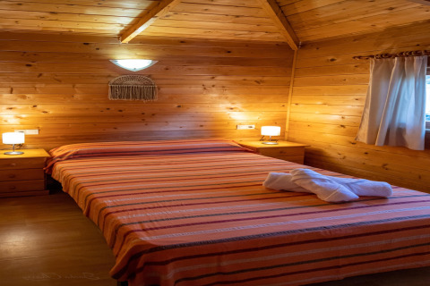 Dormitorio de madera en TORRE DEL SOL Chalet Melia, España, con cama doble, lámparas y mesitas de noche.