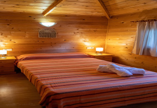 Dormitorio de madera en TORRE DEL SOL Chalet Melia, España, con cama doble, lámparas y mesitas de noche.