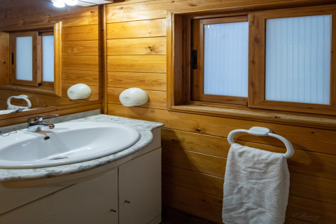 Baño con paredes de madera, lavabo blanco y toallero en Torre del Sol Chalet Melia en España.