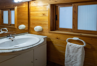 Baño con paredes de madera, lavabo blanco y toallero en Torre del Sol Chalet Melia en España.