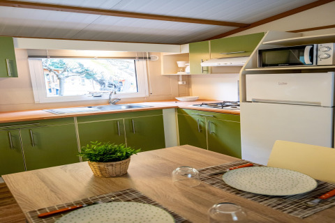 Lyst køkken i TORRE DEL SOL CHALET BAOBAD i Spanien med grønne skabe, spisekrog og udsigt ud af vinduet.