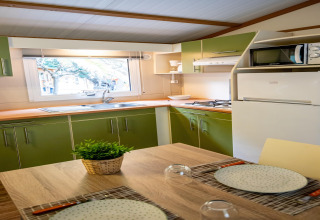 Lyst køkken i TORRE DEL SOL CHALET BAOBAD i Spanien med grønne skabe, spisekrog og udsigt ud af vinduet.