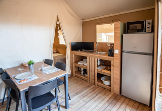 Interior of Torre del Sol TIENDA SAVANNAH safari tent in Spain, showing dining area, bed, and kitchenette.