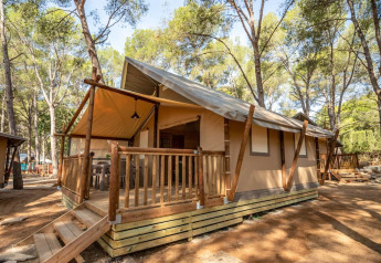 Tenda safari Torre del Sol in Spagna, immersa tra alberi, con veranda e scala d’ingresso in legno.