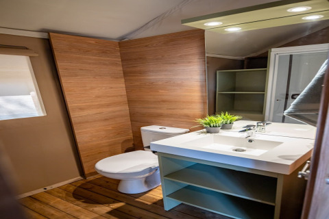 Modern bathroom with wooden walls, white fixtures and spacious sink in Torre del Sol Savannah safari tent, Spain.