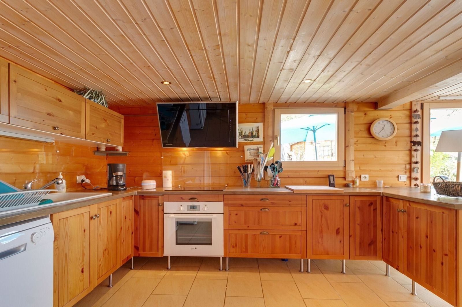 Moderne houten keuken met oven, tv en raam in Chalet «Cheylard» in Frankrijk.