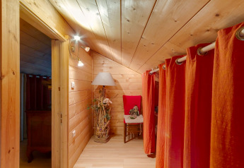 Corridoio accogliente dello Chalet Cheylard, in Francia, con pannelli in legno, tende rosse e lampada decorativa.