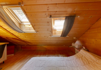 Camera mansardata allo Chalet Cheylard, in Francia, con pannelli in legno e lucernari.