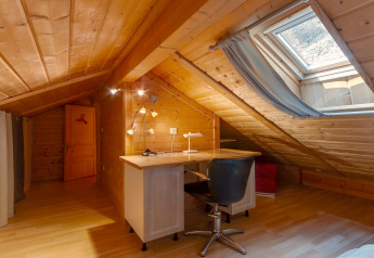 Ufficio mansardato con soffitto in legno inclinato e lucernario nel Chalet «Cheylard» in Francia.