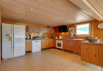 Cucina moderna nello Chalet «Cheylard» in Francia, con interni in legno, elettrodomestici e ampia finestra.