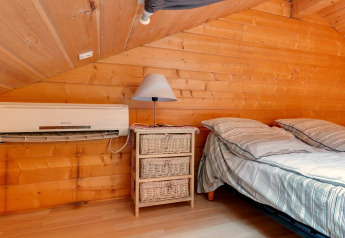 Camera da letto nello Chalet «Cheylard» in Francia con pareti in legno, aria condizionata, lampada e letto accogliente.