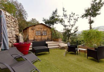 Casetta in legno con patio, mobili da giardino neri e vista panoramica al Chalet Cheylard, Francia.