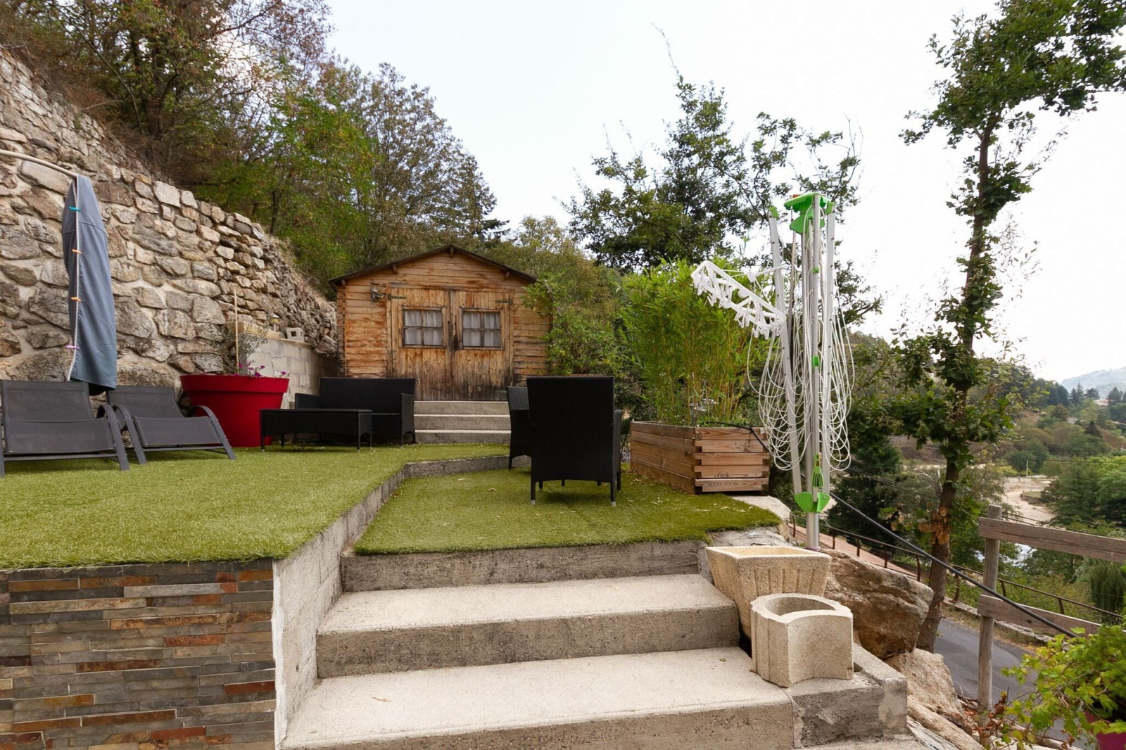 Buitenterras bij Chalet Cheylard met kunstgras, loungestoelen, droogrek en uitzicht op de bergen.