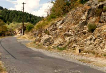 Strada asfaltata vicino a una parete rocciosa presso Chalet «Cheylard» in Francia, circondata da boschi.