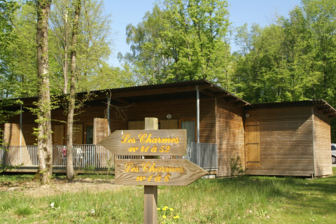 Foto van een houten lodge te midden van bomen, met wegwijzers naar verschillende kamers in het bos.