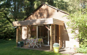 Træhytte i grønne omgivelser med terrasse og havemøbler ved Maison de vacances - LE PONCHEL i Frankrig.