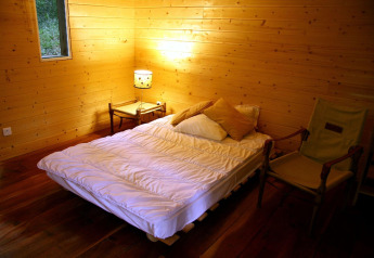 Gemütliches Schlafzimmer aus Holz im Ecolodge „en Sequoia“ in Frankreich mit einfacher Einrichtung.