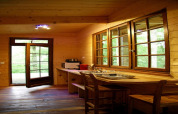 Holzinterieur der Ecolodge «en Sequoia» in Frankreich mit großen Fenstern, geöffneter Tür und Küchenzeile.