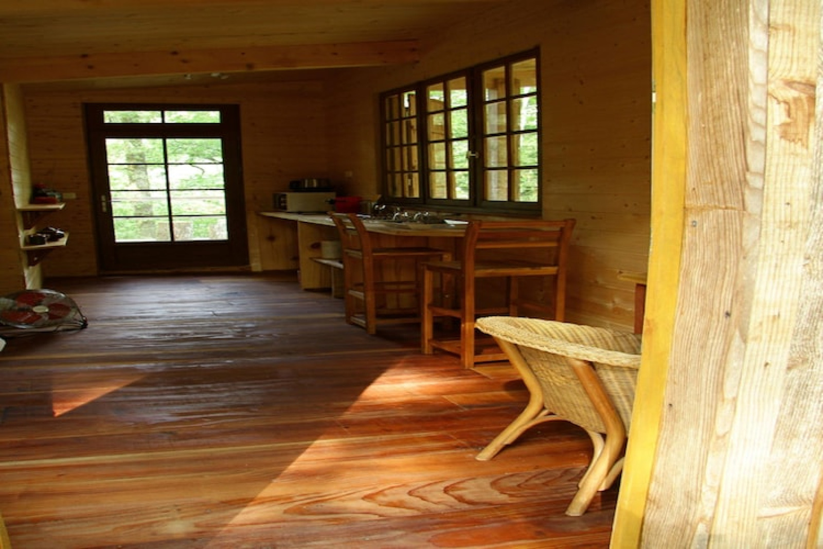 Interieur van Ecolodge «en Sequoia» hut in Frankrijk met houten vloer, meubels en grote ramen.