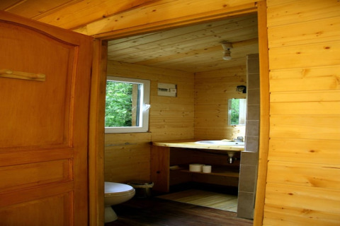 Interior view of a wooden bathroom at Ecolodge «en Sequoia» in France, with open door and window.