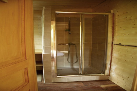Modern glass shower enclosure at Ecolodge «en Sequoia» cabin in France, viewed from the bathroom door.