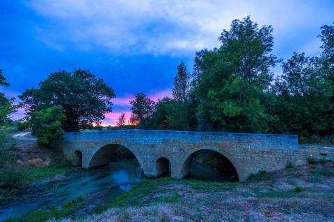 Stone bridge at sunset surrounded by trees, photographed from Ecolodge 'en Sequoia' in France, scenic view.