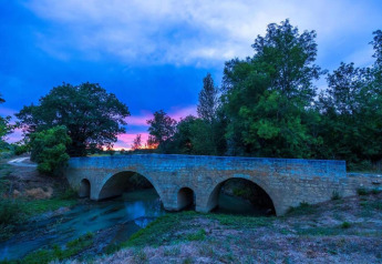 Steinbrücke bei Sonnenuntergang, umgeben von Bäumen, gesehen von Ecolodge 'en Sequoia' in Frankreich.