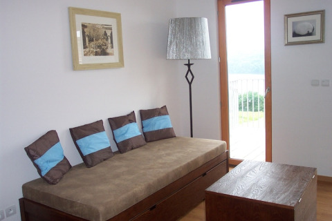 Een modern lodge-interieur met bruine sofa, blauwe kussens, lamp, houten tafel en balkon.