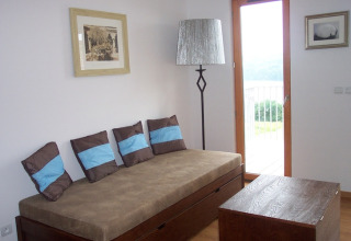 Een modern lodge-interieur met bruine sofa, blauwe kussens, lamp, houten tafel en balkon.