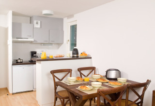 Moderne kitchenette en eetkamer in een Franse lodge, ontbijt met croissants en sinaasappelsap.