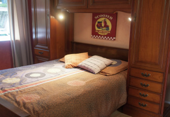 Camera da letto con letto matrimoniale, armadi in legno e segno scooter a Maison de vacances - LE PONCHEL, Francia.