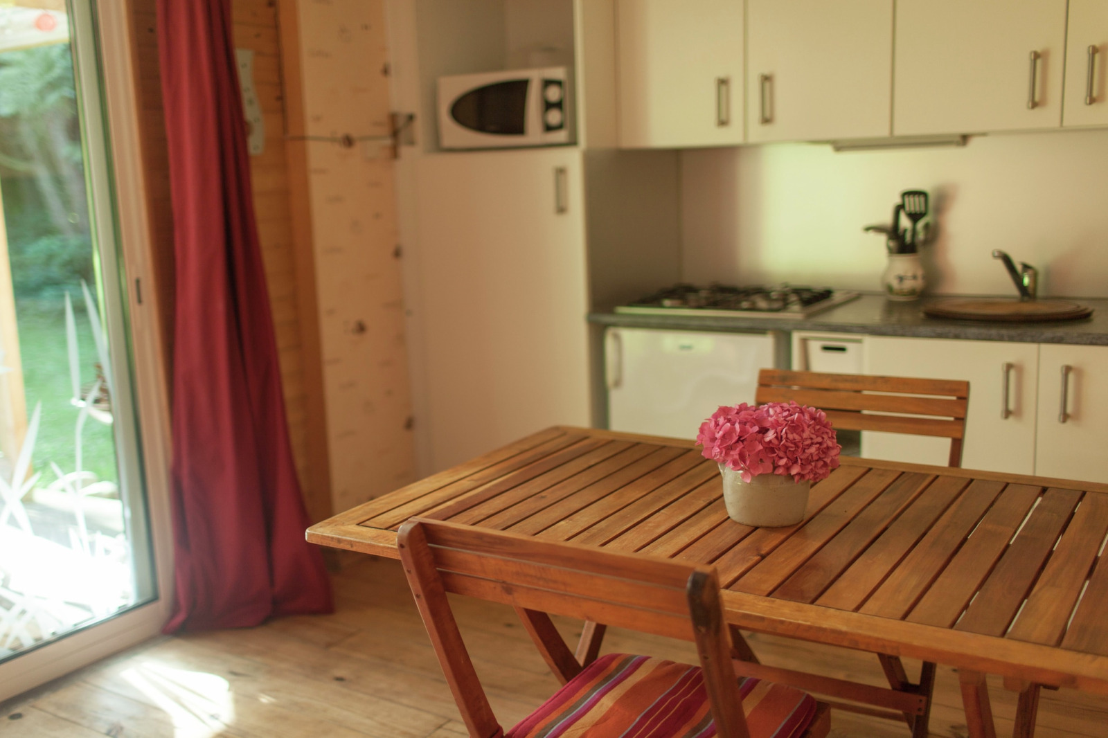 Houten tafel met bloemenvaas in de gezellige keuken van Maison de vacances - LE PONCHEL, Frankrijk.