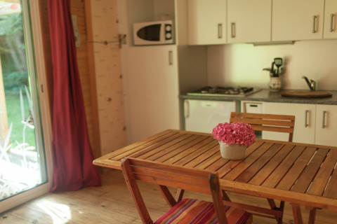 Træbord med blomsterkrukke i et hyggeligt køkkenområde på Maison de vacances - LE PONCHEL, Frankrig.