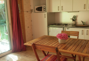 Mesa de madera con maceta de flores en la cocina acogedora de Maison de vacances - LE PONCHEL, Francia.