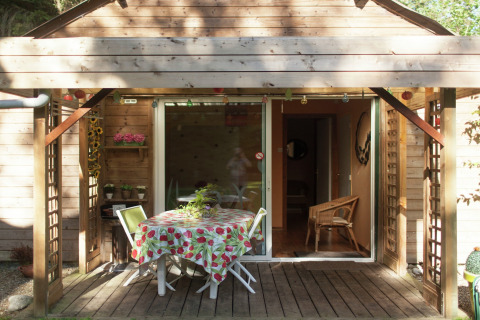 Træhytte terrasse med havebord og stole under overdækning ved Maison de vacances - LE PONCHEL i Frankrig.
