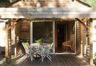 Terraza de cabaña de madera con mesa y sillas en Maison de vacances - LE PONCHEL en Francia.