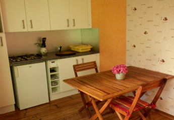 Petite cuisine de la Maison de vacances - LE PONCHEL en France, avec table en bois et bouquet de fleurs roses.