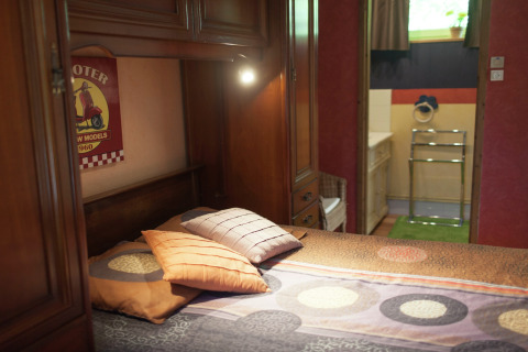 Dormitorio acogedor con muebles de madera, cojines coloridos y vista al baño en Maison de vacances - LE PONCHEL, Francia.