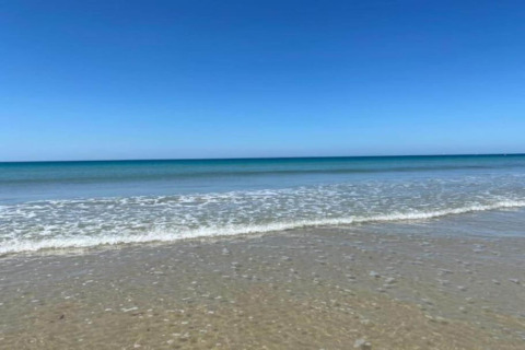 Fredelig strand med blåt hav og klar himmel ved Maison de vacances - LE PONCHEL, Frankrig.