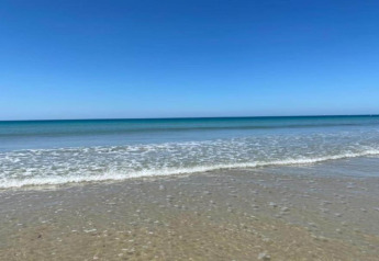 Peaceful beach with gentle waves and clear sky at Maison de vacances - LE PONCHEL, France.