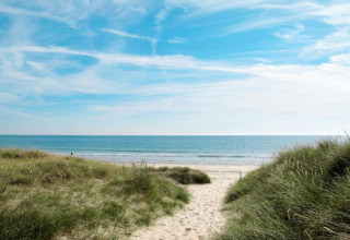 Vista de la playa desde Maison de vacances - LE PONCHEL, Francia, con dunas verdes, arena y cielo azul.